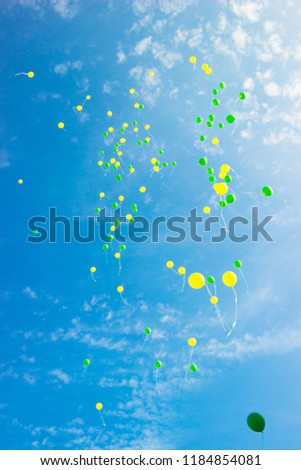 Festive multi-colored balloons in the blue sky with 
clouds