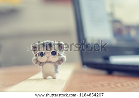 Felting toy little gray kitten in glasses on wooden stand