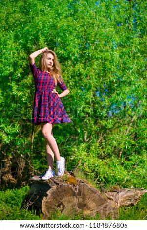 Textile, design, clothing, fashion concept. teenager showing clothes Beautiful young woman in a beautiful dress. Standing on the stump
