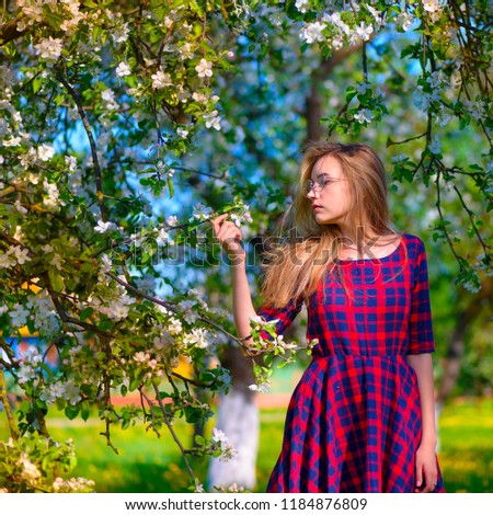Spring style. Beautiful young woman in a beautiful spring dress. Beautiful spring garden. Fashionable spring