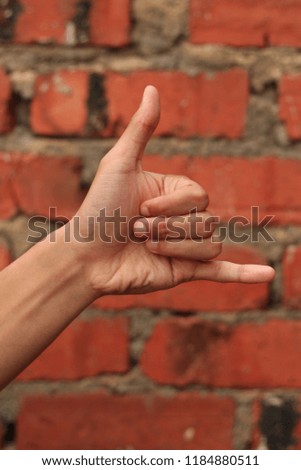 hand gesture as calling or contact sign with brick wall background. business concept. 