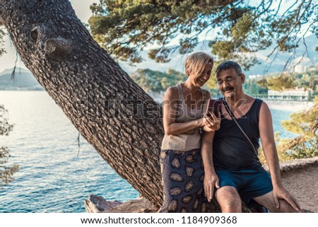 Beautiful older couple using phone and taking pictures on vacation. Summertime vacation old people using smartphone 