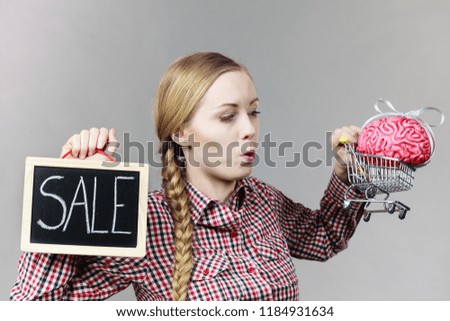 Woman holding shopping cart with brain inside and sale sign. Clever, responsible buying concept.
