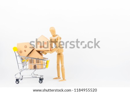 Wooden human mannequin holding shopping cart full of paper hose model, isolated on white background with copy space.Real estate concept, New house concept.Buying a house