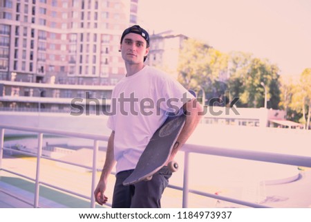 Look at me. Pleased brunette holding his skateboard while preparing for training