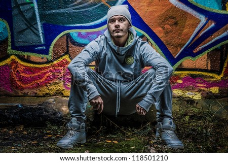 Fashion photo of young guy posing on bright wall