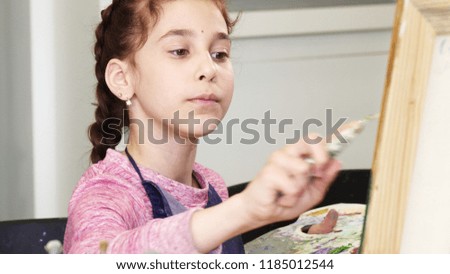 Pretty little girl holding pallette painting a picture