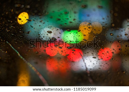 Rain drops rain on the window with blurred traffic light