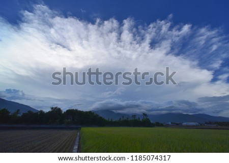 The blue sky in front of the Green Meadows is dominated by large white clouds of radial shape.