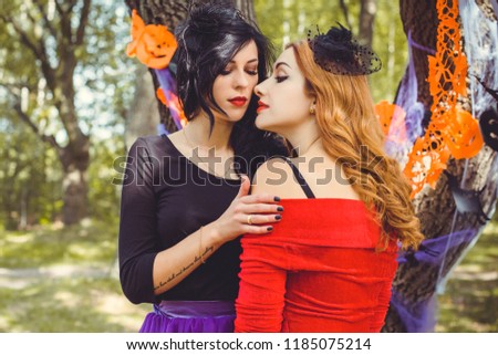 Halloween concept, glamorous costume detail.Two elegant and charming mysterious witches, magical female beauty. Portrait of gorgeous fairy wizards enchantress, on a carnaval