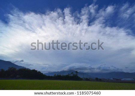 The blue sky in front of the Green Meadows is dominated by large white clouds of radial shape.