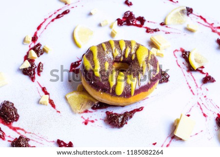 Doughnut with white chocolate and lemon on white table.