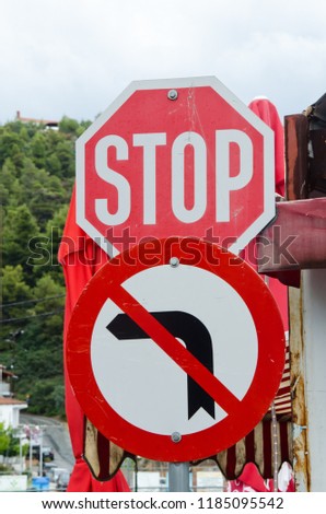 two signs, stop and forbidden turn left traffic sign,  don't turn left sign at the end of  street  close up 