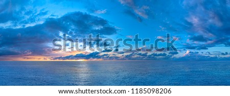 Panorama of twilight sunset over the sea with colorful clouds. Dramatic atmosphere created by the sunlight. Colorful gradient from blue to orange. High resolution panoranic sky. Royalty-Free Stock Photo #1185098206