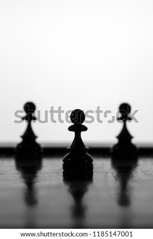 Pawns chess pieces with the center pawn standing out on a white background
