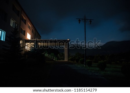 Mountain night landscape of building at forest at night with moon or vintage country house at night with clouds and stars. Summer night. Photo taken with long exposure
