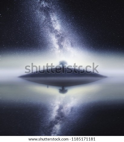 Surreal landscape with man standin on small island on endless sea under stars.