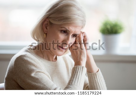 Thoughtful sad mature middle aged woman feeling blue melancholic worried concerned about problems, upset serious depressed senior old lady widow thinking of anxiety depression, grieving lost love Royalty-Free Stock Photo #1185179224