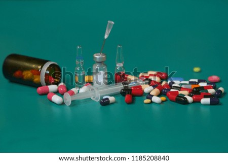Medication capsules in an opened prescription bottle. Medicine, capsules, tablets, injection, syringe and needle. Close-up of various drugs on green background                               