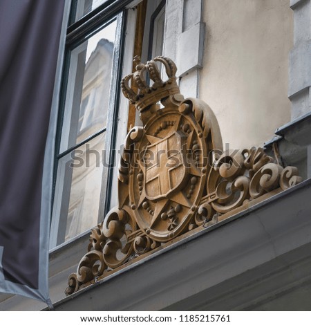 Wooden carved emblem with crown on the facade of the building