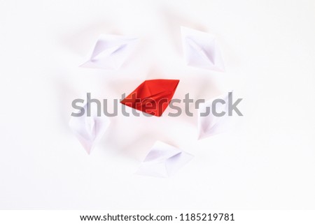 Red paper boat among other white. Leadership, white crow, individuality. Piranhas and a shark. Not like everyone else. Origami. Top view, flat lay, copy space.
