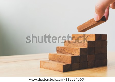Hand arranging wood block stacking as step stair. Ladder career path concept for business growth success process Royalty-Free Stock Photo #1185240634