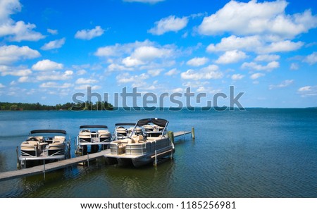 Boat dock with raised pontoons on beautiful lake in northern Minnesota with blue sky and fluffy clouds Royalty-Free Stock Photo #1185256981