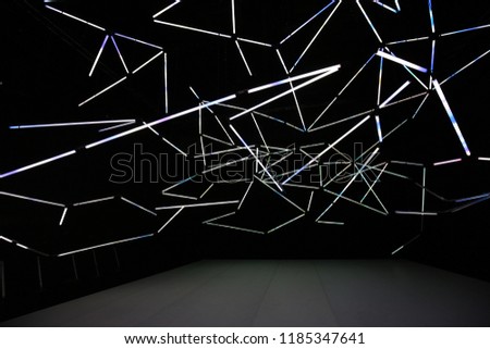 Abstract view of illuminated neon lights in an area dedicated to dance. Many white lines with a black background. Stage in the foreground. Geometric shapes created by electricity. Graphic design.