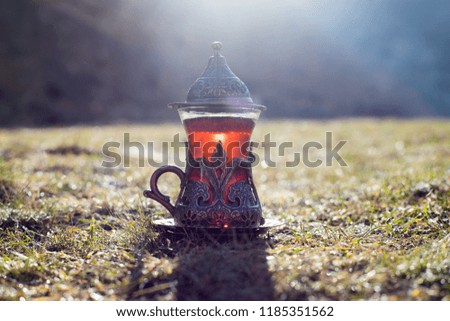 Eastern black tea in glass outdoor mountains background. Eastern tea concept. Armudu traditional cup. Green nature summer background. Selective focus