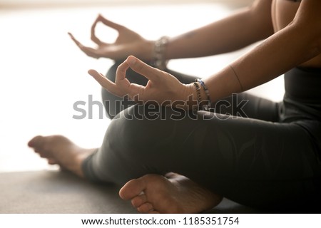 Sporty yogi woman practicing yoga, meditating in Easy Seat exercise, Sukhasana pose with mudra gesture, working out, wearing sportswear, indoor hands close up, at yoga studio. Hobby wellbeing concept Royalty-Free Stock Photo #1185351754
