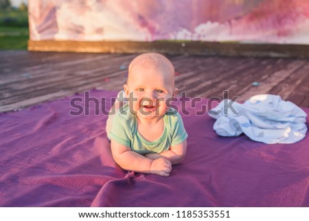 Cute child baby boy lying on blanket in summer day on nature. Family picnic in a park.