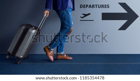 Traveling Concept, Young Traveler Walking with Suitcase and Follow the Departures Sign in the Airport Royalty-Free Stock Photo #1185354478