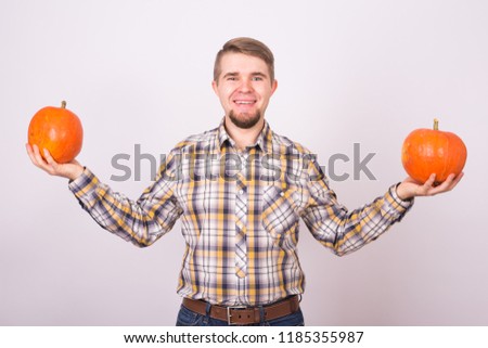 Smiling man holding pumpkins over white background. Harvest and autumn concept