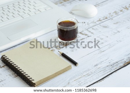 Note book and black coffee on the desk.