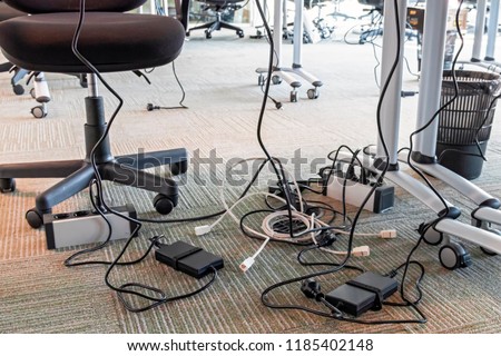 Concept of clutter in office. Unwound and tangled electrical wires under the table. 5S system of lean manufacturing Royalty-Free Stock Photo #1185402148