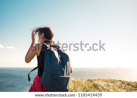 Young woman with backpack on the background of the sky. Girl tourist outdoor, soft focus image