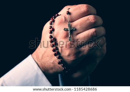 Male hands praying holding a rosary with Jesus Christ in the cross or Crucifix on black background. Mature man with Christian Catholic religious faith Royalty-Free Stock Photo #1185428686