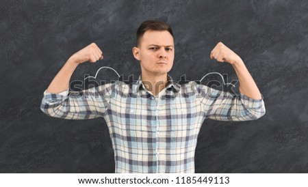 Young man standing against background of depicted muscles on chalkboard. Self confidence concept, motivation poster