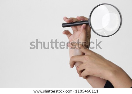 Hand holding magnifying glass over white background. 