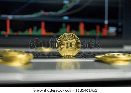 Golden Dash coin with gold coins lying around on a black keyboard of silver laptop and diagram chart graph on a screen as a background. Mining of dash online bussiness. Trading.