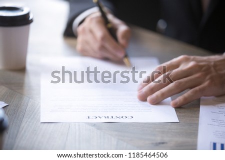 Man in suit fills name form and signs contract with a business partner, employment or insurance contract. Client signs the contract. Recruitment, hiring process human resources, close up view