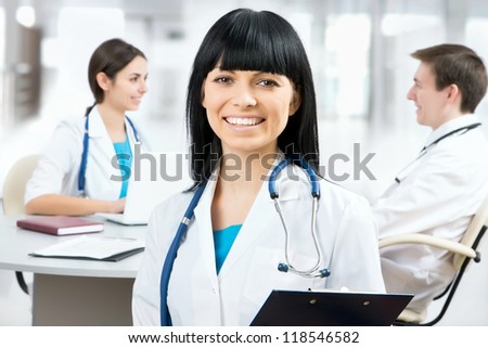 Portrait of young female doctor standing in frount of his team and smiling