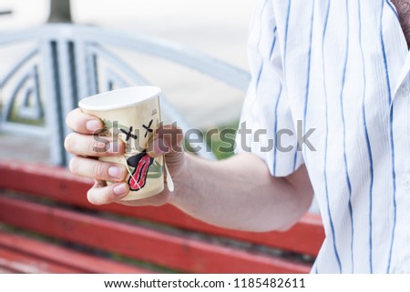 An animated disposable cup of coffee is tormented and dies and suffers in the hands of an evil person, who squeezes and squeezes it
