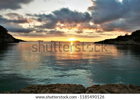 sunset in Ibiza,dawn in Ibiza,with some clouds on the horizon, golden yellow sun and golden sun wake in the sea, a calm Mediterranean Sea,