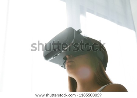Young female playing game in VR glasses. Beautiful woman using modern virtual reality glasses