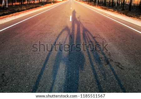 Shadow of unrecognizable cyclist riding a bike in urban surrounding.