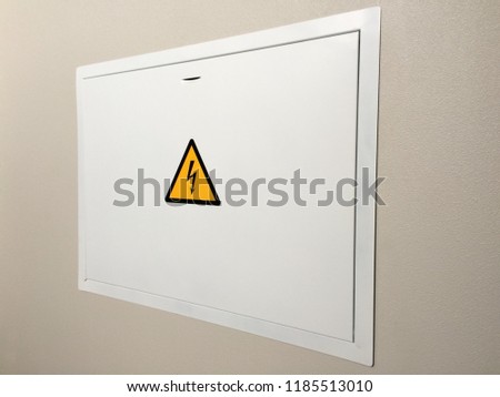 Gray hinged power supply unit on the wall, electric flap, danger sign