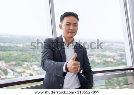 portrait of smiling chinese businessman 
show thumb up on the top of building