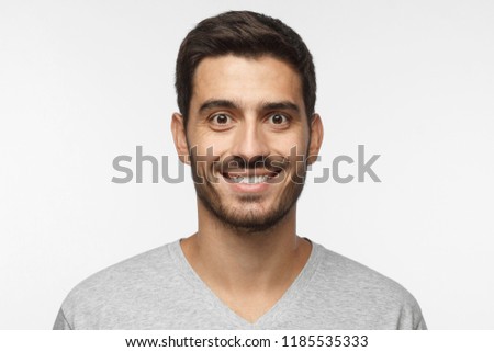 Close up portrait of smiling handsome man in gray t-shirt isolated on gray background