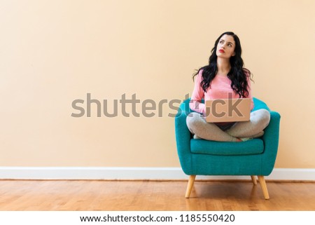 Young woman using a laptop computer in a chair